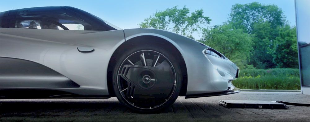 Side view of the McLaren Speedtail approaching the base pad, which lays on the ground just in front of the car.