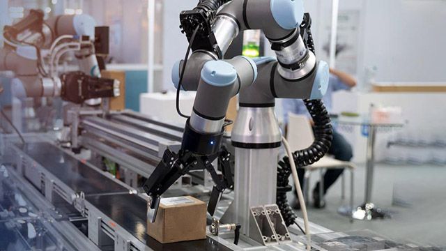 A cobot puts a cardboard package on a conveyer belt.