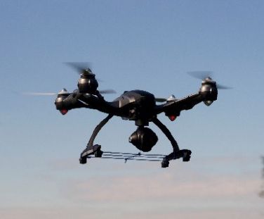 Image of a drone flying with a Lidar mounted on top of it.